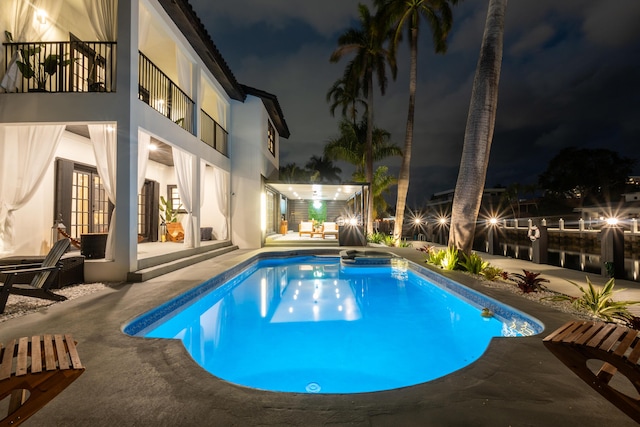 pool at twilight featuring a patio area