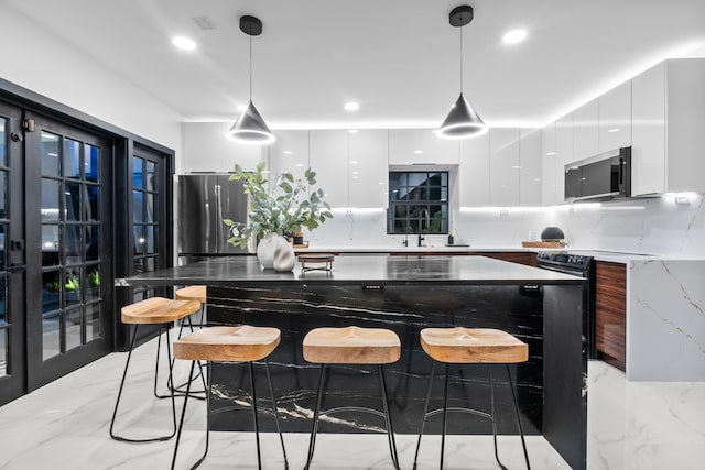 kitchen featuring white cabinetry, sink, light stone counters, and decorative light fixtures