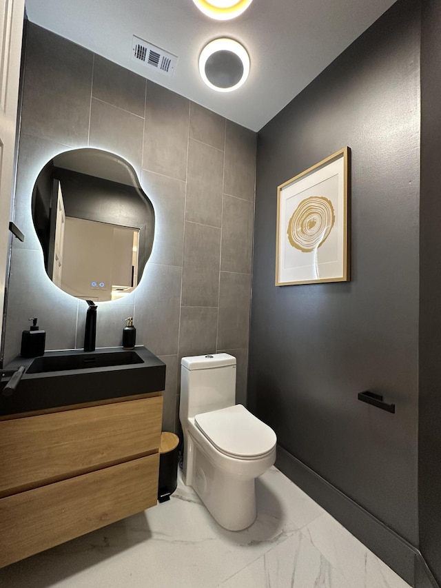 bathroom with vanity, toilet, and tile walls