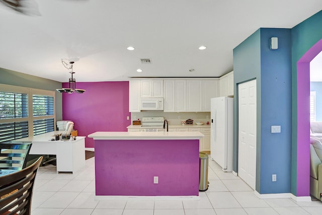 kitchen with white appliances, light tile patterned floors, white cabinets, hanging light fixtures, and an island with sink