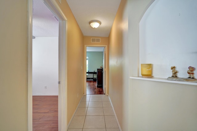 hall with light tile patterned floors and a textured ceiling