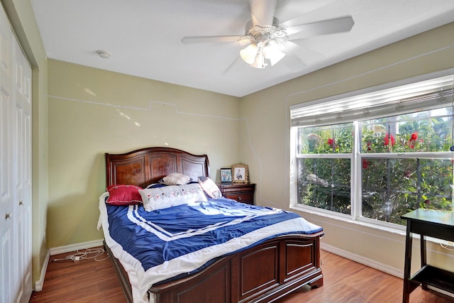 bedroom featuring multiple windows, hardwood / wood-style flooring, a closet, and ceiling fan