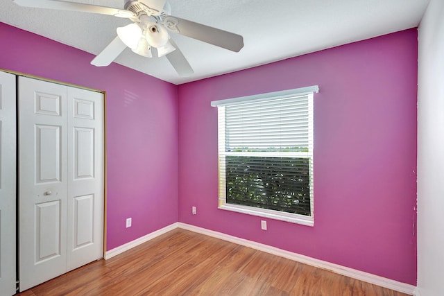 unfurnished bedroom featuring ceiling fan, light hardwood / wood-style flooring, and a closet