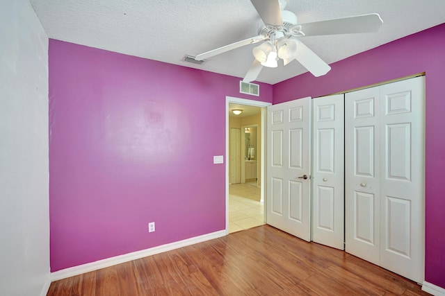 unfurnished bedroom featuring ceiling fan, a closet, hardwood / wood-style floors, and a textured ceiling