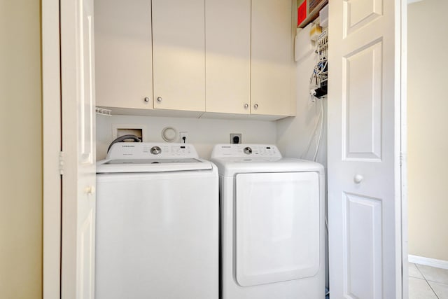 laundry area featuring cabinets, washer and dryer, and light tile patterned flooring