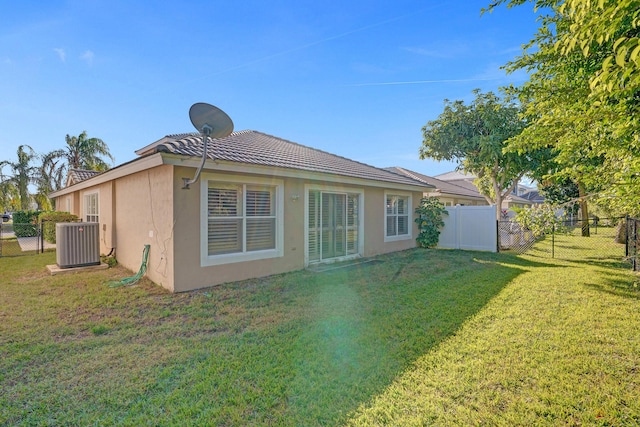 back of house with central AC and a lawn