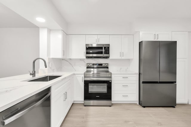 kitchen featuring light stone countertops, white cabinetry, sink, and stainless steel appliances