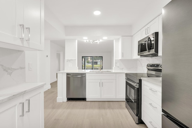 kitchen with light stone countertops, white cabinetry, sink, stainless steel appliances, and backsplash