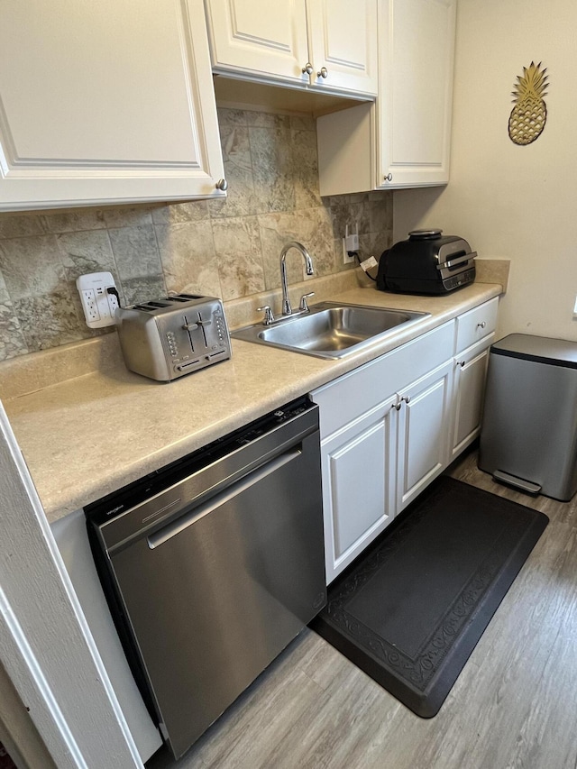 kitchen with white cabinetry, sink, stainless steel dishwasher, and light hardwood / wood-style flooring