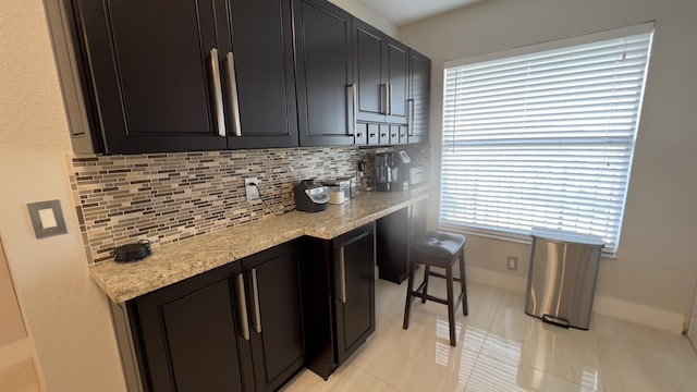 kitchen featuring tasteful backsplash, light stone counters, plenty of natural light, and light tile patterned flooring