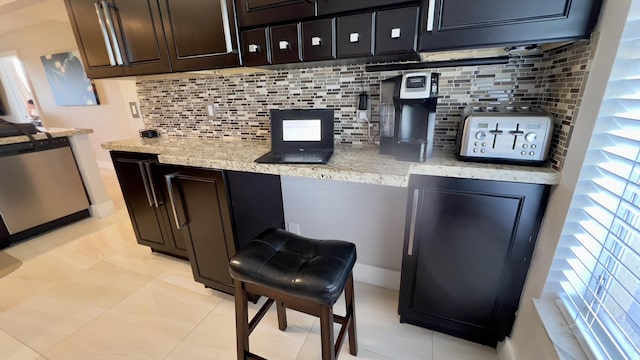 bar with stainless steel dishwasher, decorative backsplash, dark brown cabinetry, and light tile patterned floors