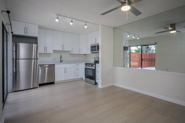 kitchen with stainless steel appliances, light wood-type flooring, white cabinetry, ceiling fan, and sink