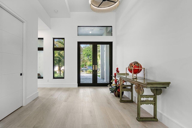 entryway with french doors, light hardwood / wood-style floors, and a high ceiling