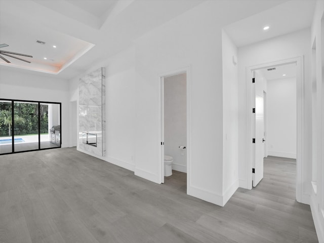 interior space featuring a tray ceiling, ceiling fan, and light hardwood / wood-style floors