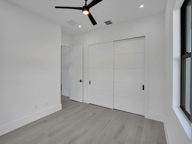 unfurnished bedroom featuring a closet, light hardwood / wood-style flooring, and ceiling fan