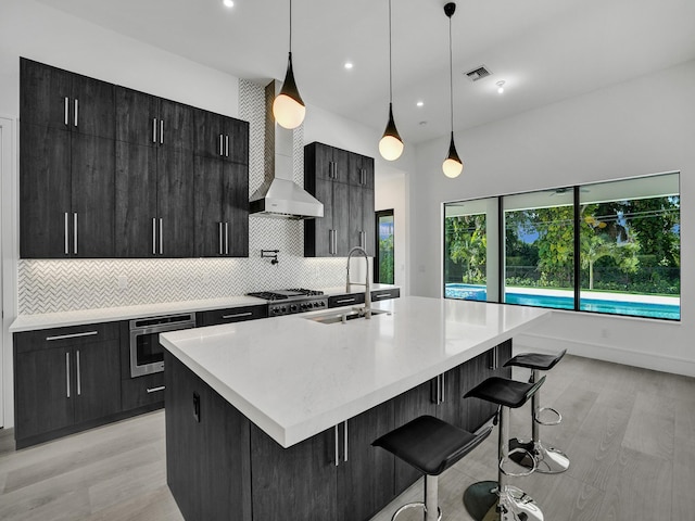 kitchen with oven, sink, hanging light fixtures, and a kitchen island with sink