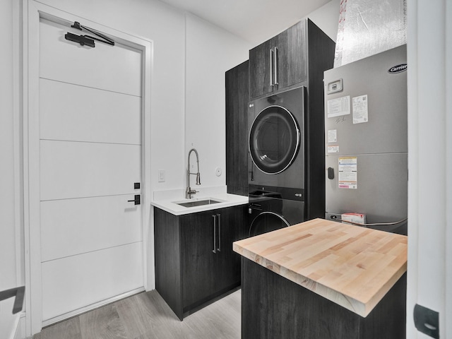 washroom featuring cabinets, light wood-type flooring, stacked washing maching and dryer, and sink