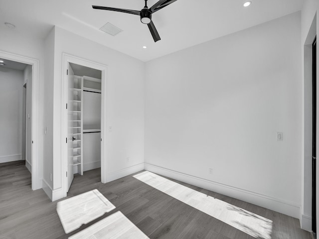 unfurnished bedroom with hardwood / wood-style floors, a closet, a spacious closet, and ceiling fan