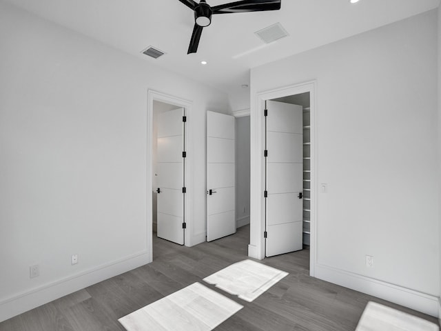 unfurnished bedroom featuring ceiling fan, a closet, a walk in closet, and light hardwood / wood-style flooring