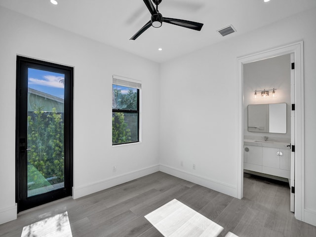 unfurnished bedroom with ceiling fan, ensuite bath, sink, and light hardwood / wood-style flooring