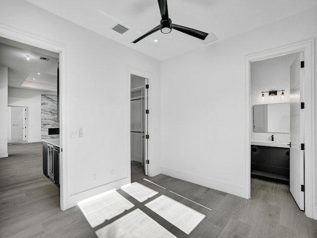 bedroom featuring a fireplace, ensuite bathroom, ceiling fan, and hardwood / wood-style flooring