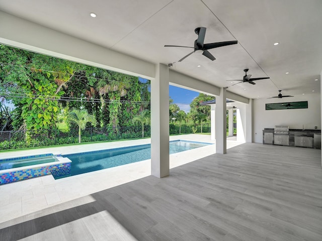 view of swimming pool with area for grilling, an in ground hot tub, and an outdoor kitchen