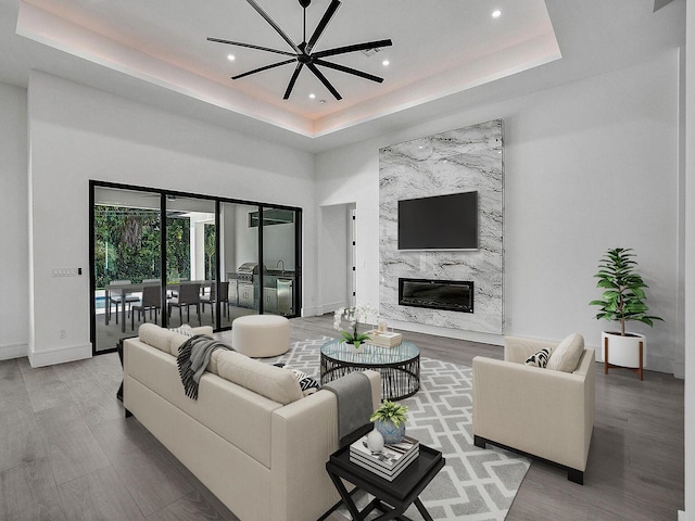 living room featuring a tray ceiling, a fireplace, and hardwood / wood-style flooring