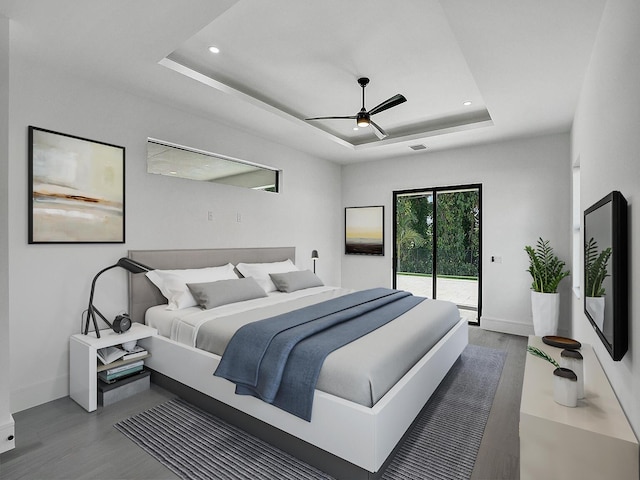 bedroom featuring hardwood / wood-style floors, ceiling fan, a raised ceiling, and access to outside