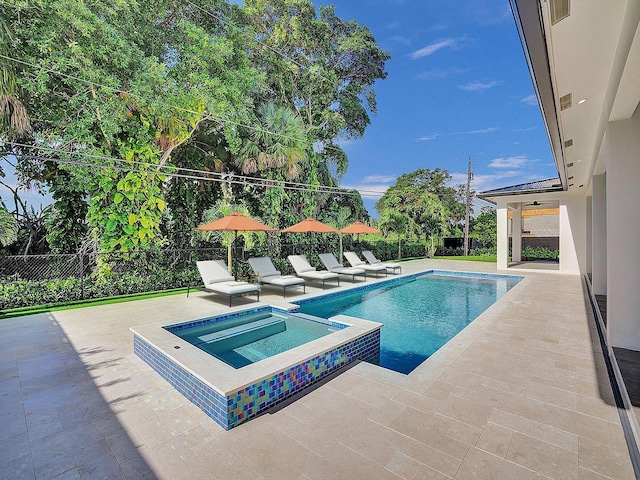 view of swimming pool featuring ceiling fan, a patio area, and an in ground hot tub