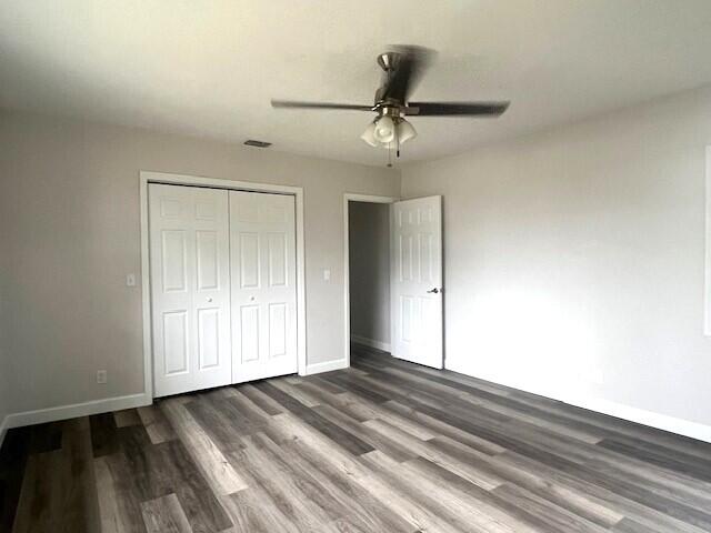 unfurnished bedroom featuring ceiling fan, a closet, and dark hardwood / wood-style floors