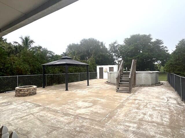 view of patio featuring a gazebo, a swimming pool, and an outdoor fire pit