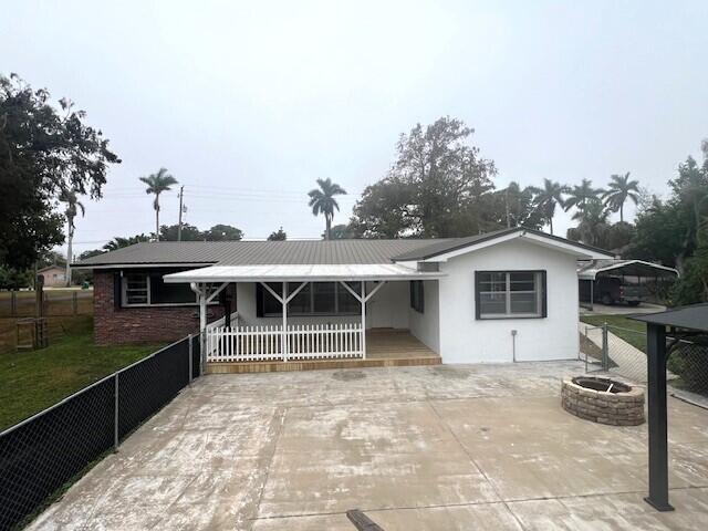 back of property with a fire pit and a porch