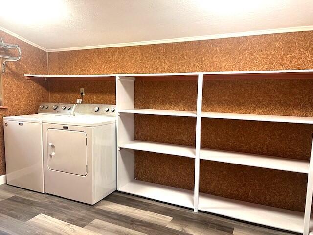 laundry area with hardwood / wood-style flooring, crown molding, and washing machine and clothes dryer