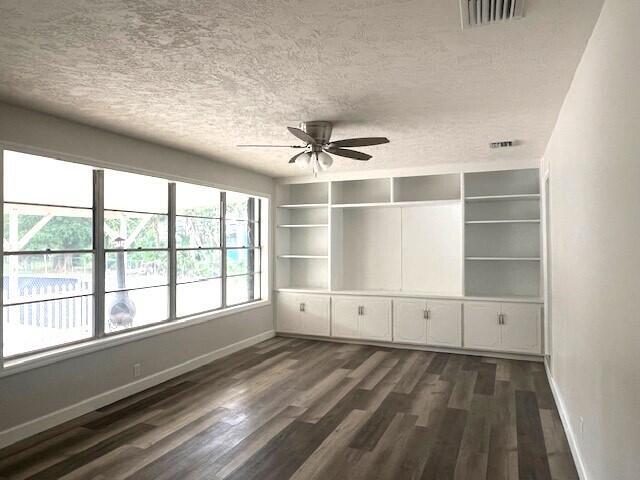 unfurnished room with a textured ceiling, ceiling fan, and dark wood-type flooring