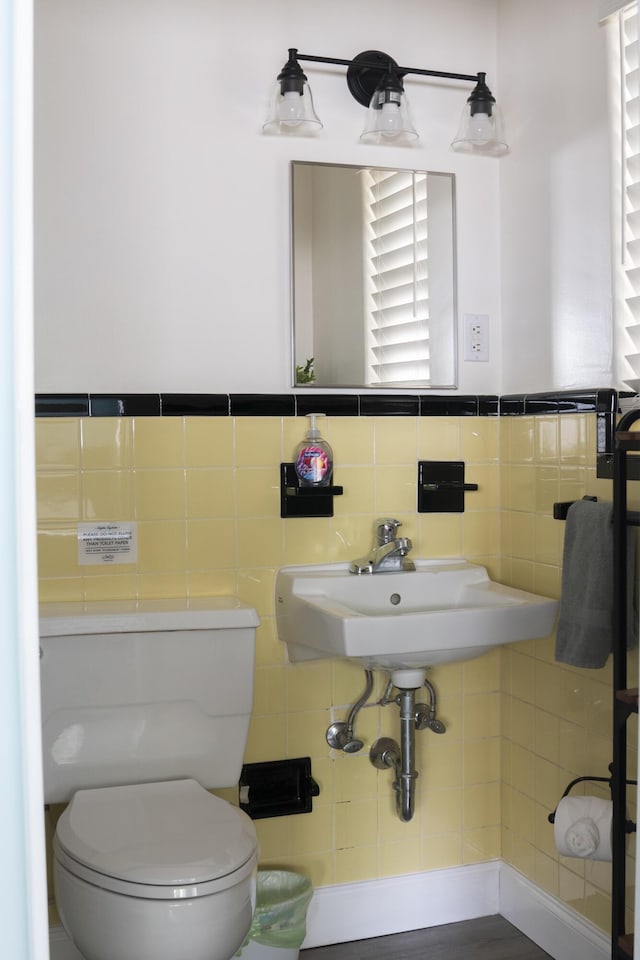 bathroom with toilet, tile walls, and sink