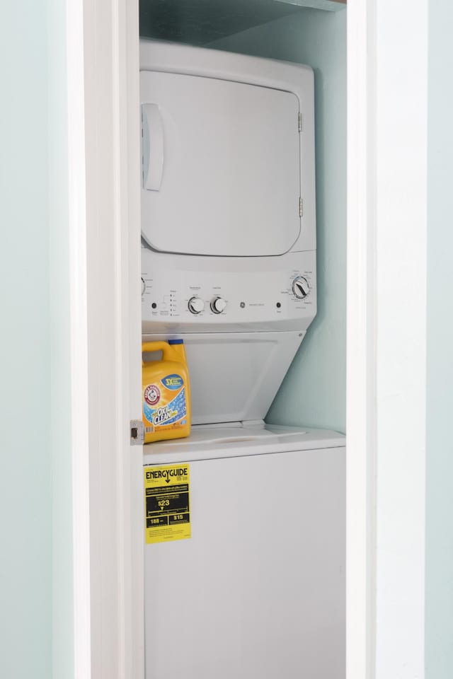 laundry area featuring stacked washing maching and dryer and light hardwood / wood-style floors