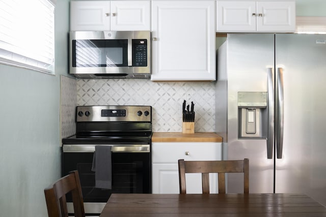 kitchen with wood counters, white cabinets, vaulted ceiling with beams, tasteful backsplash, and stainless steel appliances