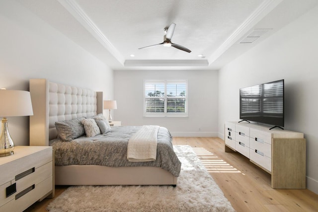 bedroom with ceiling fan, ornamental molding, a raised ceiling, and light wood-type flooring