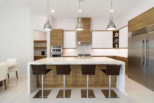 kitchen with pendant lighting, white cabinetry, stainless steel appliances, backsplash, and a kitchen island with sink