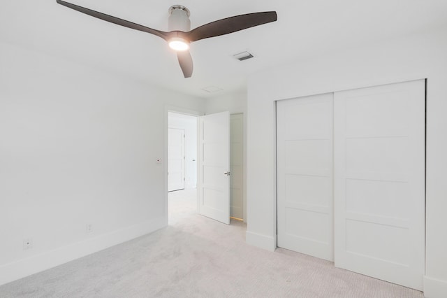 unfurnished bedroom with ceiling fan, light colored carpet, and a closet