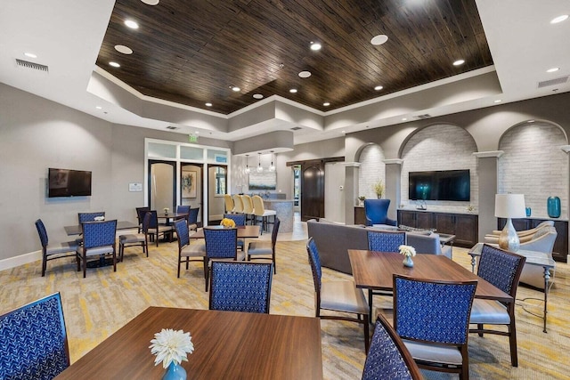 dining area with light hardwood / wood-style floors, wooden ceiling, a tray ceiling, brick wall, and crown molding