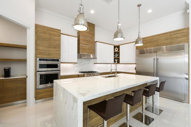 kitchen featuring white cabinetry, stainless steel appliances, a kitchen breakfast bar, hanging light fixtures, and a center island with sink