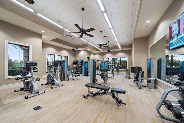 workout area with a towering ceiling and light hardwood / wood-style flooring