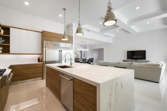 kitchen featuring sink, white cabinetry, beam ceiling, and an island with sink