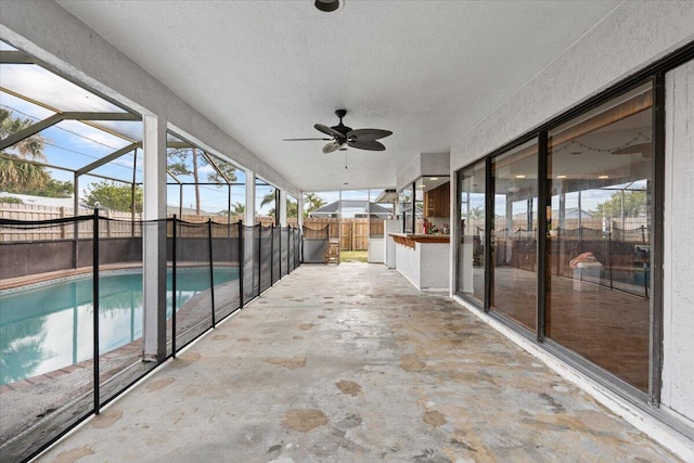 view of patio featuring glass enclosure, a fenced in pool, a fenced backyard, and a ceiling fan