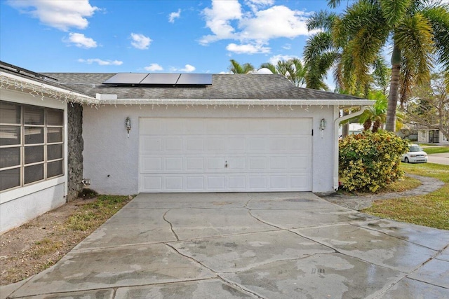 garage with solar panels and driveway