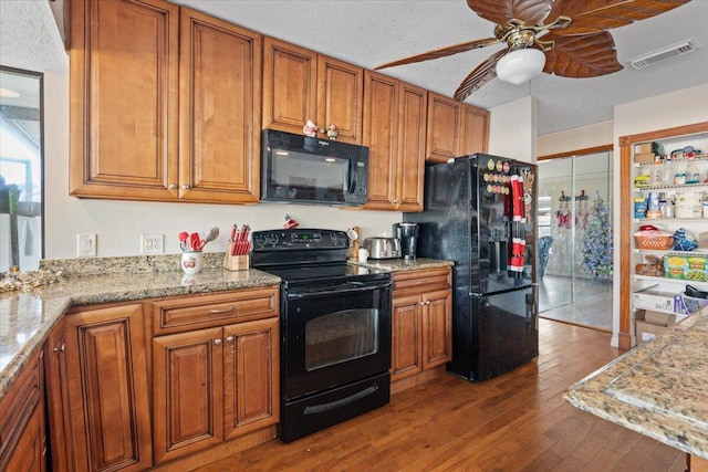 kitchen with visible vents, ceiling fan, hardwood / wood-style floors, brown cabinetry, and black appliances