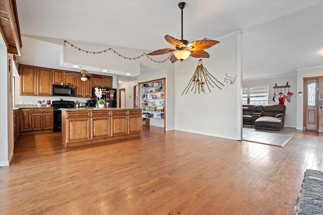 kitchen with light wood-type flooring, black appliances, ornamental molding, open floor plan, and brown cabinetry