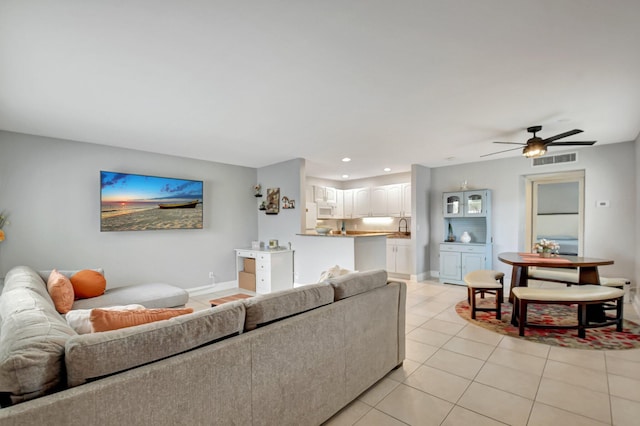 living room featuring ceiling fan, light tile patterned floors, and sink