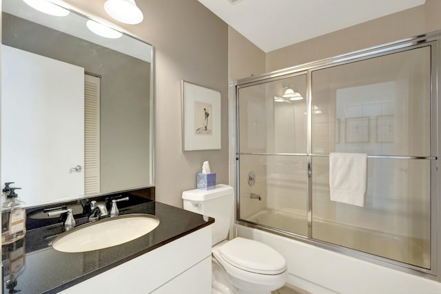 full bathroom featuring vanity, enclosed tub / shower combo, and toilet